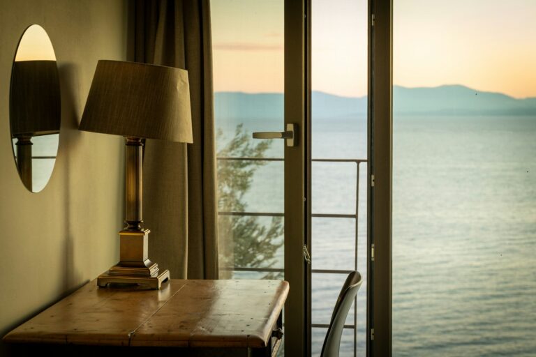 Φωτιστικό σε τραπεζάκι δίπλα στο παράθυρο με θέα στη θάλασσα